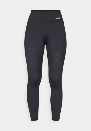 Mustat korkeavyötäröiset legginssit, joissa on sileä pinta, varustettuna brändätyllä vyötärönauhalla ja kahdella vaakasuoralla raidalla reidessä yksityiskohtia varten.