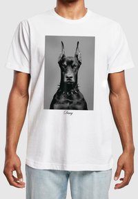 Bílá bavlněná tričko s černobílým portrétem dobermana s hroty na obojku. Pod obrázkem je text "Dawg".