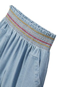 Pantalon en denim bleu clair avec une taille froncée et des accents brodés colorés en rouge, or et bleu. Comprend des poches latérales.