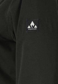 Zwart jassenmateriaal met een gladde textuur, voorzien van een prominente vierkante logopatch in zwart en wit. Het logo heeft driehoekige ontwerpen.