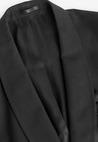 Blazer negro con acabado satinado. Los detalles notables incluyen un forro interior estampado, solapas con muesca y una textura suave.