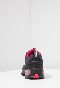 Black athletic shoes with pink interior and grey accents. Features a breathable mesh design, textured sole, and pull tab at the back.