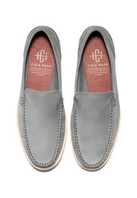 Grå slip-on skor med slät läder, en stitchad tå och en ljusgummisula med en röd innersula.