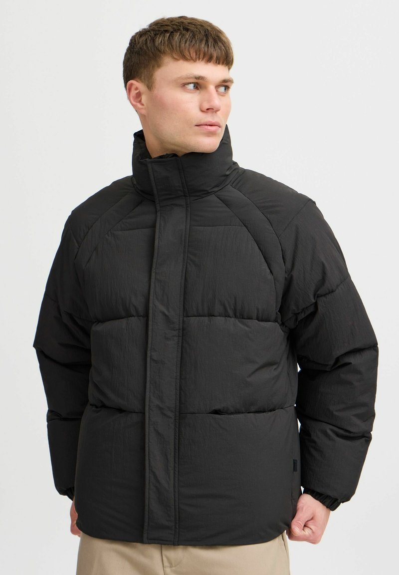 Sort puffjakke med høj krave, kviltet design og elastiske manchetter. Stoffet ser glat ud med en mat finish.