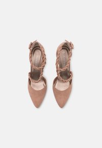 Beżowe zamszowe buty na wysokim obcasie z ostro zakończonym noskiem, z plecionym paskiem i zapięciem na klamrę przy kostce. Rozmiar 37.