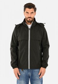 Giacca impermeabile nera con collo alto, zip bianca e strisce in contrasto. Presenta polsini elasticizzati e due tasche laterali con zip. Vestibilità casual.