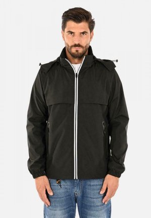 Giacca impermeabile nera con collo alto, zip bianca e strisce in contrasto. Presenta polsini elasticizzati e due tasche laterali con zip. Vestibilità casual.