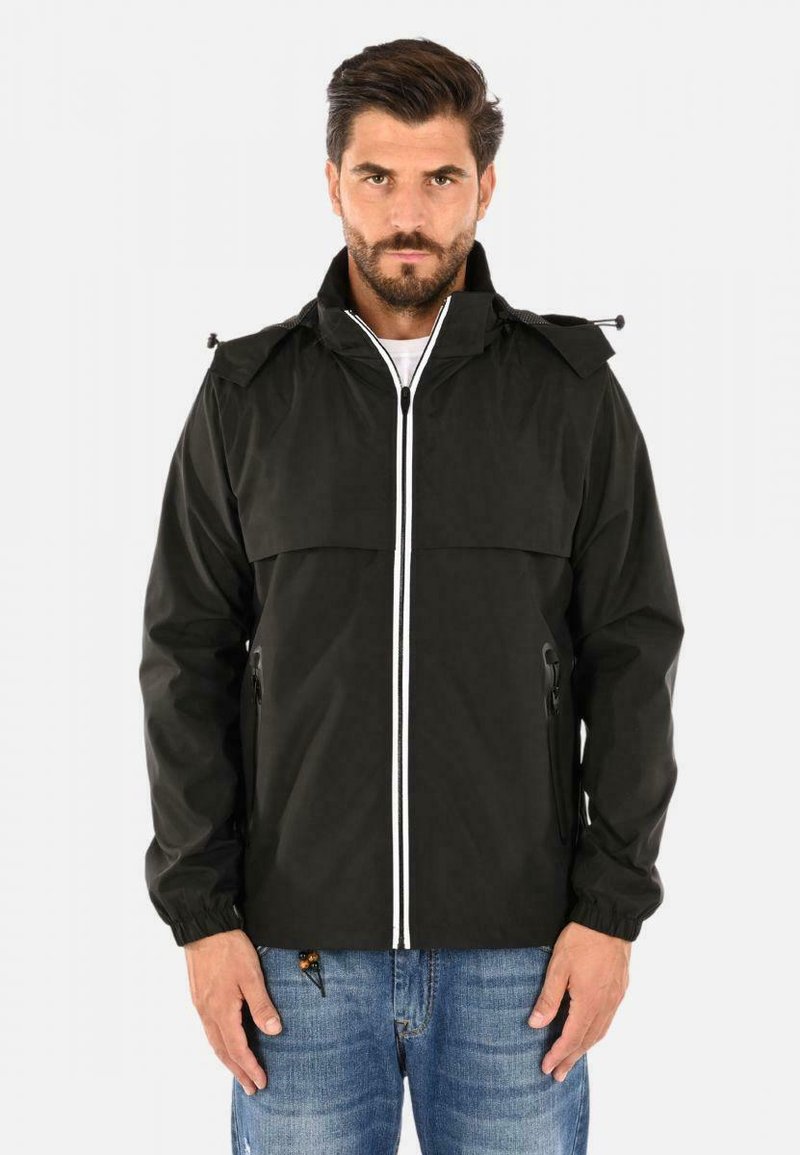 Giacca impermeabile nera con collo alto, zip bianca e strisce in contrasto. Presenta polsini elasticizzati e due tasche laterali con zip. Vestibilità casual.