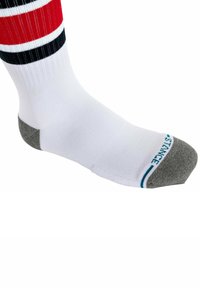 Weißes Sportsocke mit roten und schwarzen Streifen, grauem Absatz und Zehen, gerippter Textur und blauer Markenkennung am Kragen.