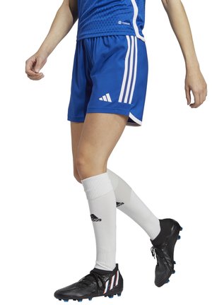 Blauwe sportshorts met witte accentstrepen, gecombineerd met kniehoge witte sokken en zwarte voetbalschoenen met blauwe en rode details.