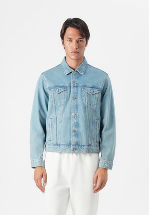 Veste en denim bleu clair avec un col classique, fermeture à boutons, deux poches poitrine et poches latérales. Présente un design légèrement court et un tissu texturé.