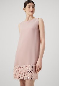 Vestido rosa sem mangas com uma textura suave e uma bainha acentuada por lantejoulas fofas, apresentando fios rosa suave e detalhes cintilantes na parte inferior.