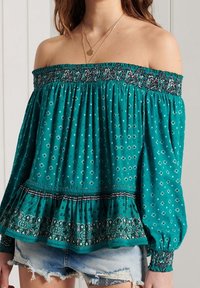 Tyrkysová off-shoulder blůza s elastickým nařaseným výstřihem, květinovým vzorem, volánkovým lemem a dlouhými rukávy s elastickými manžetami.