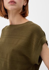 Olive green textured knit sweater with wide neck, short sleeves, and alternating horizontal stripes of raised patterns and smooth bands.