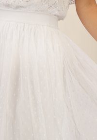 Falda de tul blanca con un patrón de lunares, que cuenta con una cinturilla suave y una textura en capas y aireada.