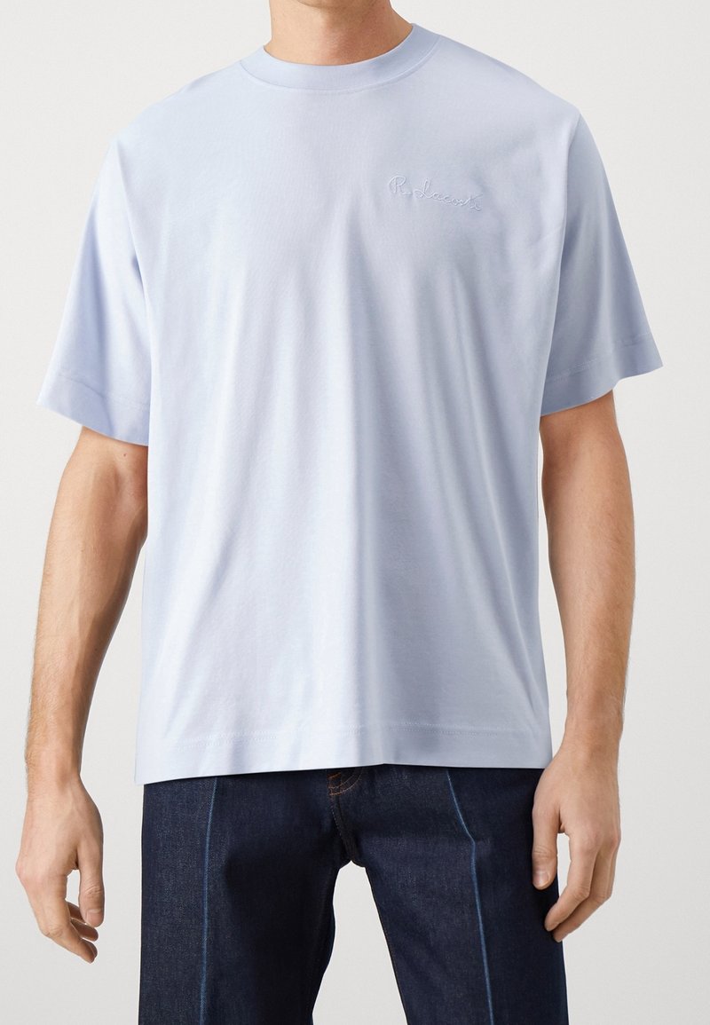 Camiseta de algodón de color azul claro con cuello redondo, mangas cortas y logo bordado en el pecho. Textura suave y corte relajado.