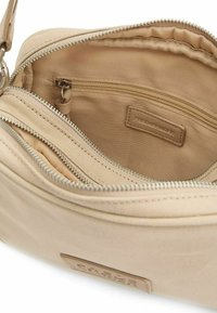 Beige schoudertas met een ritssluiting, uitgerust met meerdere binnenzakken, van gladde stof en met een leren merkiem binnenin.