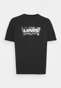 T-shirt en coton noir avec un grand logo Levi's blanc orné de motifs noirs et blancs complexes. Encolure classique et manches courtes.