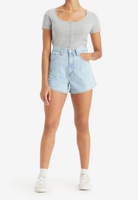 Gray ribbed short-sleeve top with button closure paired with high-waisted light blue denim shorts. White sneakers complete the outfit.