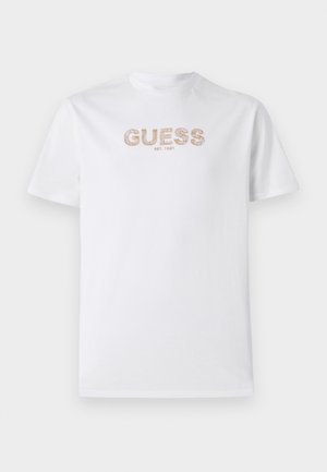 Fehér pamut póló kerek nyakkivágással és rövid ujjakkal. Jellemzője a "GUESS" logó dombornyomott világosbarna színben, alatta az "EST. 1981" felirattal.