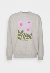 Felpa grigia chiaro con tre grandi fiori lavanda con centri arancioni e foglie verdi, testo "KAOTIKO SOCIETY" sotto il design.