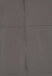 Gros plan sur un tissu gris avec une fermeture éclair verticale et deux coutures horizontales cousues le traversant.