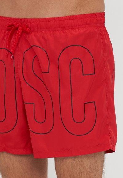 Červené plavky vyrobené z ľahkého, hladkého materiálu s veľkým čiernym grafikom "OSC" na boku a nastaviteľným pásom na šnúrku.