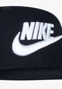 Czarna czapka o strukturalnym designie. Posiada białe, haftowane logo "NIKE" oraz swoosh. Teksturowana tkanina z detalami szycia.