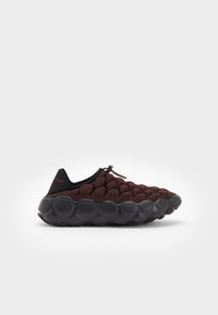 Red and black textured sneakers with a unique bubble-like sole. Slip-on design with laces, featuring a prominent curved outsole.