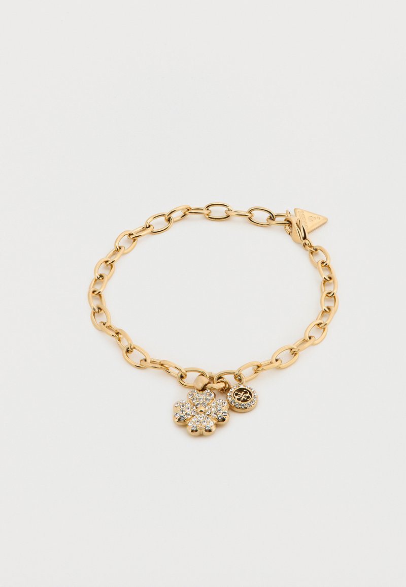 Βραχιόλι με αλυσίδα από χρυσό μέταλλο που διαθέτει ένα μενταγιόν σε σχήμα λουλουδιού διακοσμημένο με διάφανα κρύσταλλα και ένα κυκλικό μενταγιόν με λεπτομέρεια λογότυπου.