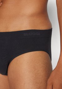 Schwarze Baumwollunterhose mit glatter Textur und elastischem Bund, versehen mit einem dezenten "Sloggi"-Logo in Dunkelgrau auf dem Bund.