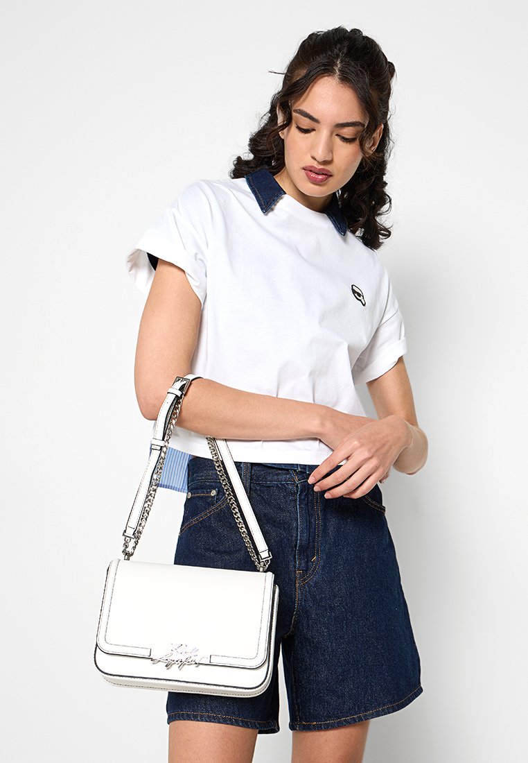 Sac à main synthétique blanc avec fermoir à rabat, bandoulière en chaîne et accents en logo argent. Présente un design structuré et une texture lisse.