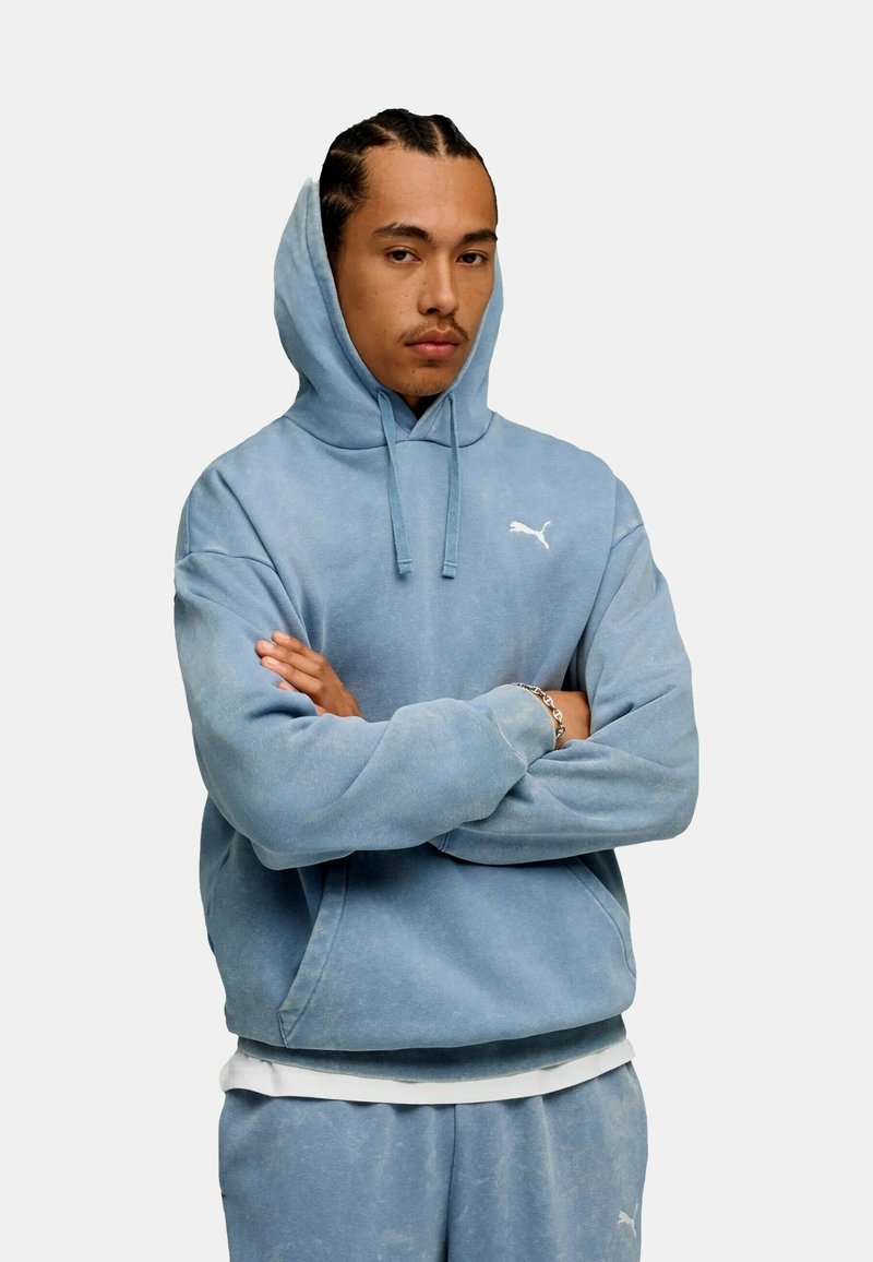 Jasnoniebieska hoodie wykonana z miękkiego materiału, z kangurzą kieszenią i białym logo na piersi. Wygodne, luźne dopasowanie.