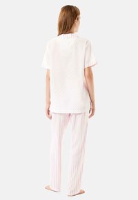 Conjunto de pijama de manga corta y cuello en blanco con un patrón de puntos rosas, acompañado de pantalones a rayas rosas y blancos, fabricado en una tela suave y transpirable.