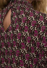 Braunes Kleid mit floralem Muster, versehen mit rosa Blumen und schwarzen Akzenten. Es hat einen hohen Ausschnitt und eine Schlüssellochöffnung im Rücken.