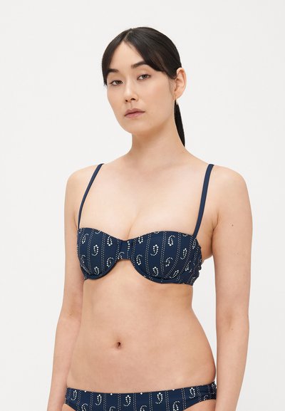 Top bikini blu navy con ferretto, caratterizzato da un motivo paisley e accenti bianchi, con sottili spalline regolabili e una texture del tessuto liscia.