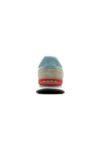 Sneaker with a light blue suede upper, beige accents, red rubber heel, and black sole. Features a logo on the heel and textured fabric.