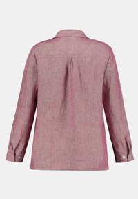 Camicia di lino rosa con maniche lunghe e bottoni, vista da dietro, con una piega centrale e polsini bottati.