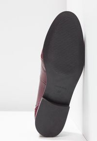 Semelle d'une chaussure en cuir bordeaux montrant une semelle extérieure en caoutchouc noir, taille 37 et marquages « Made in Spain ».