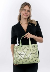 Borsa a mano con motivo geometrico verde e finitura lucida, con accenti neri e due manici robusti. Forma rettangolare, realizzata in materiale sintetico.