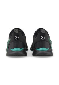 Svarta sportskor med gröna detaljer. Funktioner inkluderar en slät textur, logodetaljer och en vadderad sula för stöd.