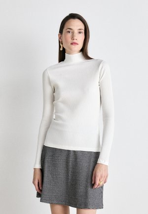 Ribbet hvit turtleneck genser med lange ermer, kombinert med et svart-og-hvitt rutete skjørt, som har en subtil tekstur og en tettsittende design.