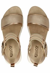 Opálené sandály s síťovanými popruhy, nastavitelnými přezkami a polstrovanou stélkou. Lehká bílá podešev. Logo značky viditelné uvnitř.