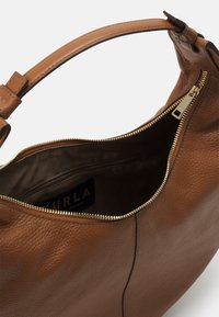 Brun læder håndtaske med gylden lynlås, buet håndtag og indvendig lynlåslomme, der viser et mærkelabel.