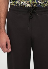 Dark gray jogger pants with a drawstring waistband. Made of soft material, featuring a slim fit and minimalistic design.