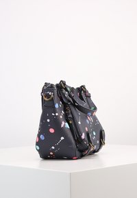 Musta teksturoitu nahkalaukku, jossa on värikäs maalisuihkureunus, useita vetoketjuja ja kultasävyistä metalliosaa. Pyöreä muoto, jossa on kerrottu yläosa.