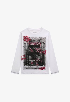 White long-sleeve t-shirt featuring a black and white graphic print of a building and red text, with contrasting stitching along the hem.