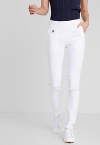 Witte, nauwsluitende broek met een hoge tailleband, zijzakken en een kleine metalen accent. Gemaakt van glad, rekbaar materiaal.