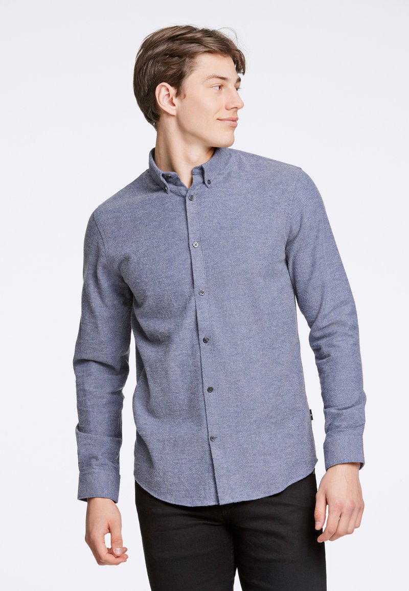 Niebieska koszula z długim rękawem, uszyta z fakturowanej tkaniny, z kołnierzykiem i zaokrąglonym dołem, z czarnymi guzikami.