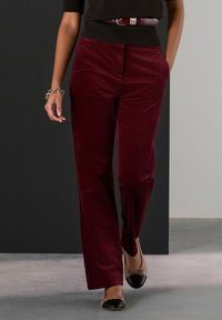 Burgundowe spodnie z sztruksu o prostym kroju, z przednimi kieszeniami i gładką fakturą, w połączeniu z beżowymi baletkami.